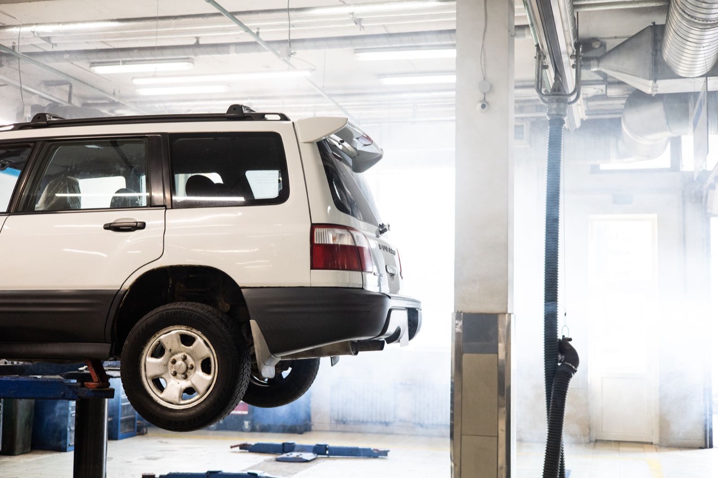 White SUV raised on a two-post lift in a bright service bay