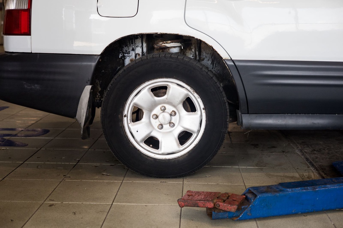 Wheel of a raised vehicle with a hydraulic jack in a service shop